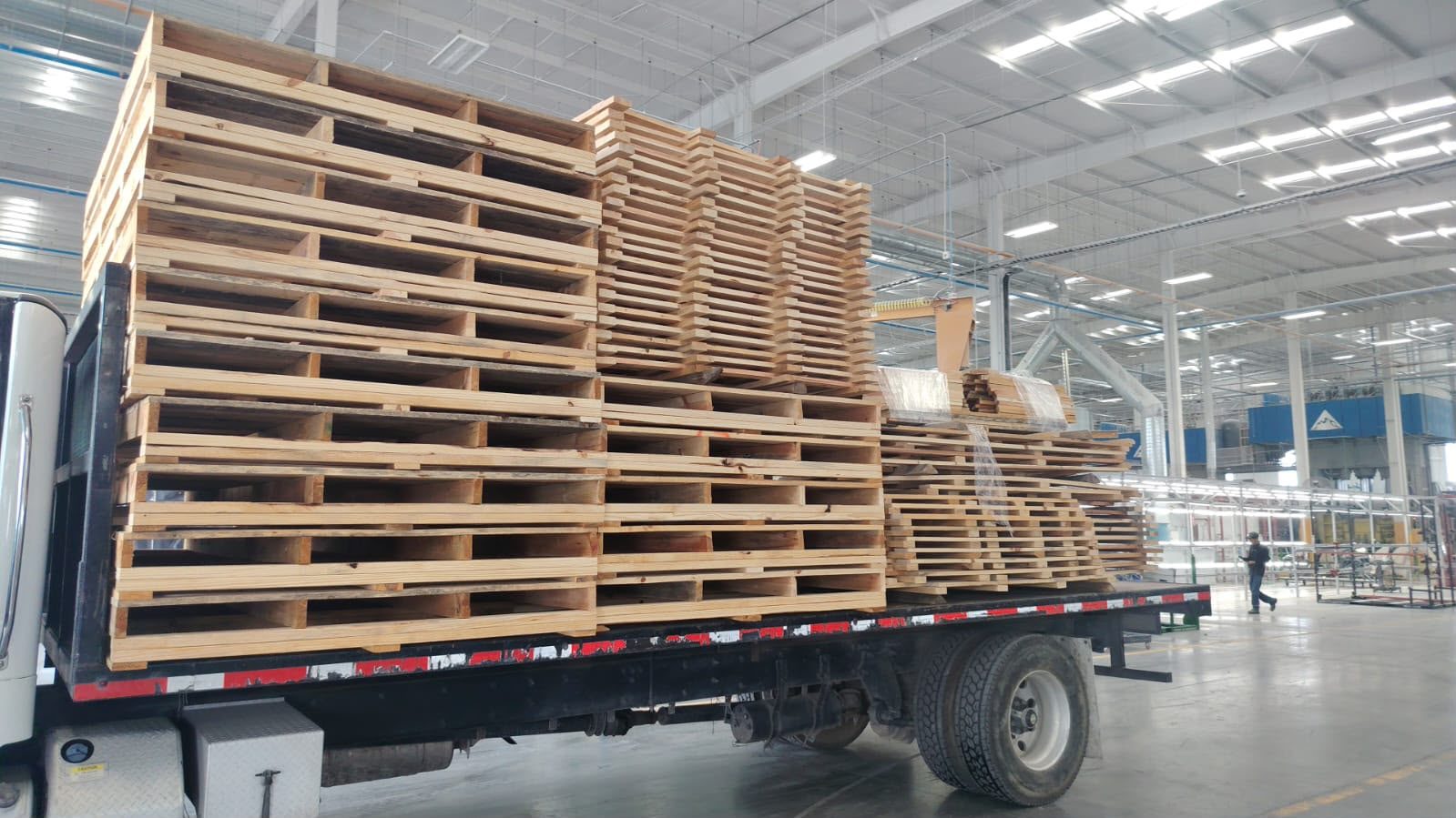 Camión cargado con tarimas de madera nuevas dentro de la planta