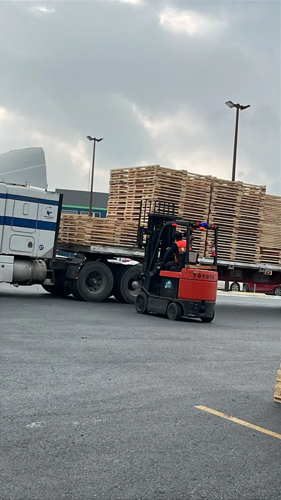 Montacargas maniobrando tarimas de madera junto a la plataforma