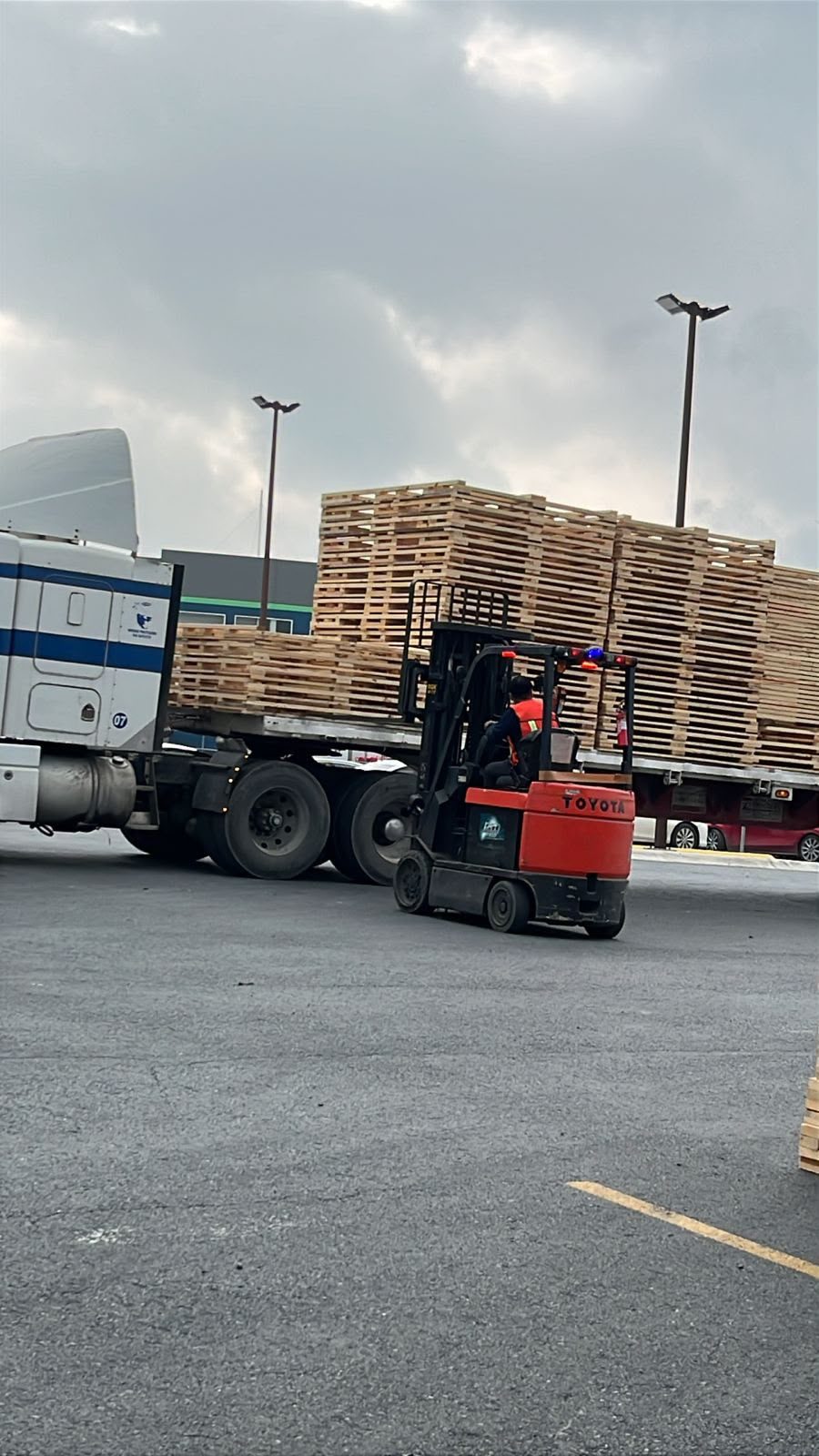 Montacargas maniobrando tarimas de madera junto a la plataforma
